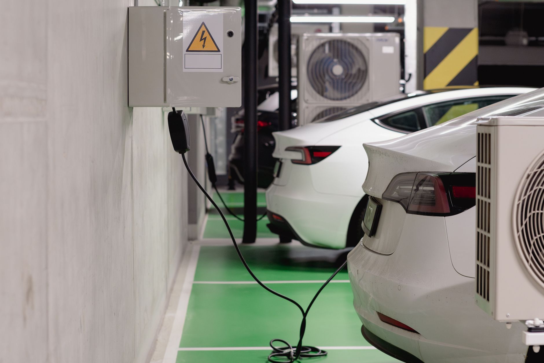 White Tesla Powerwall battery mounted on a garage wall beside an electrical panel.