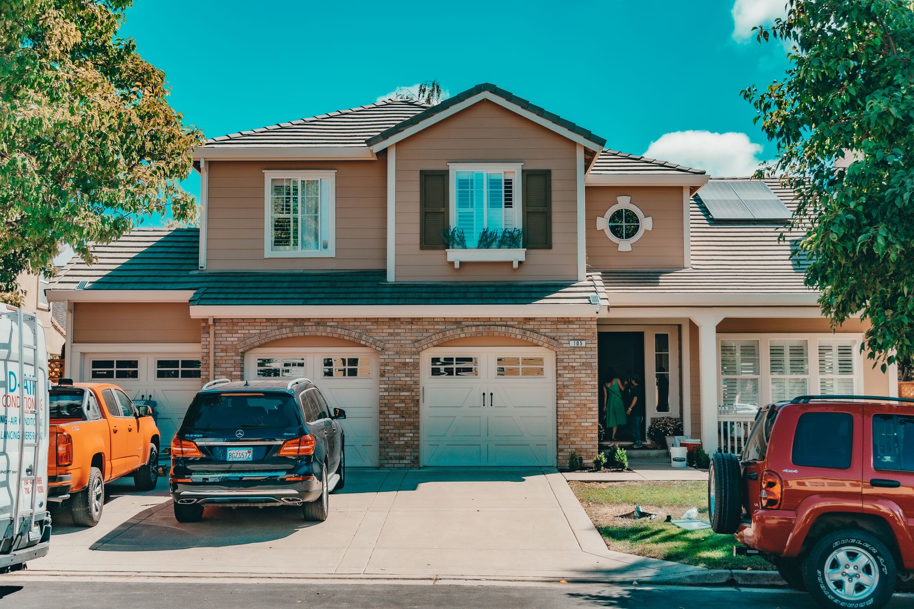 Rooftop solar panels on a suburban home with an electric car parked in the driveway