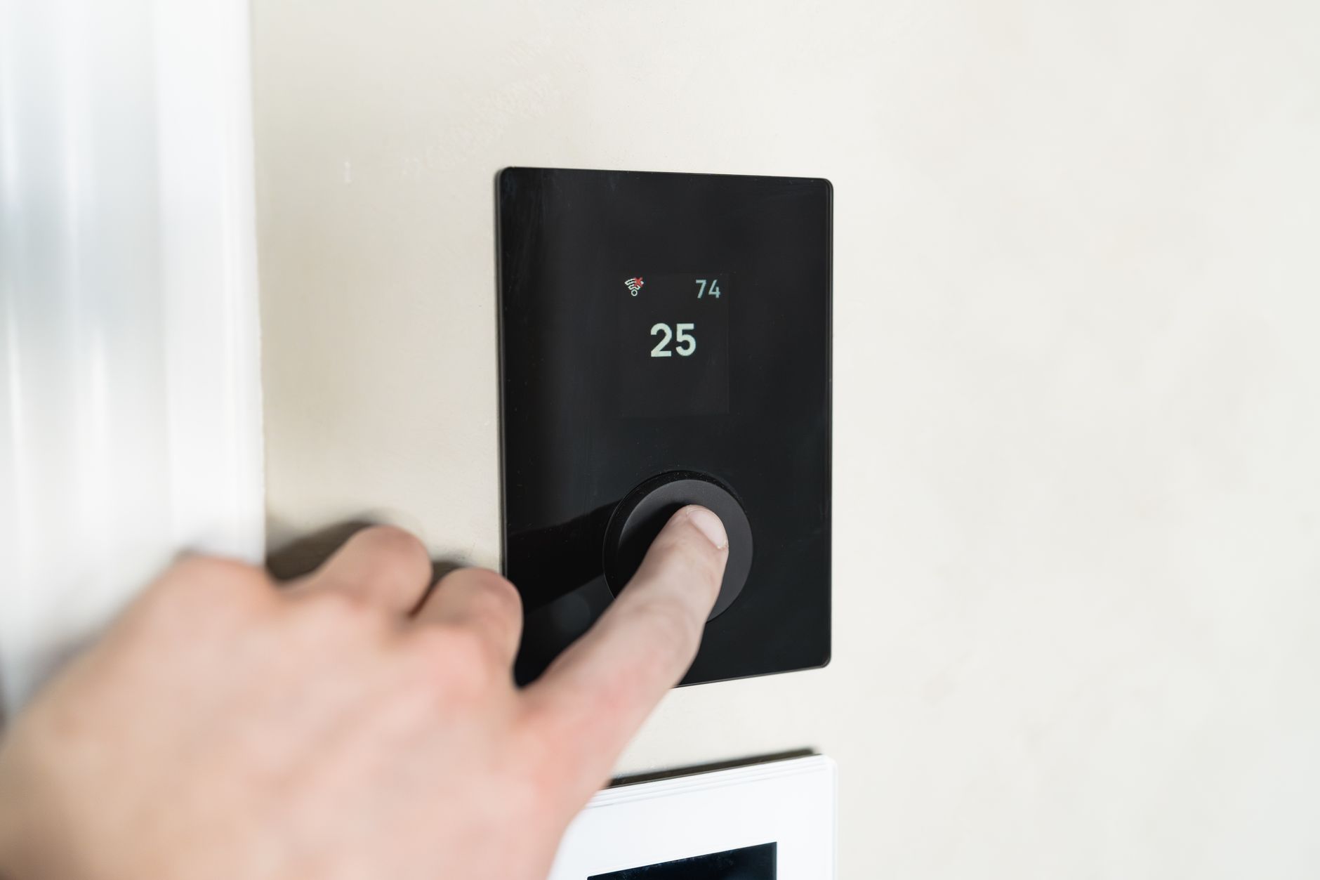 A smart thermostat mounted on a living room wall, showing a temperature schedule