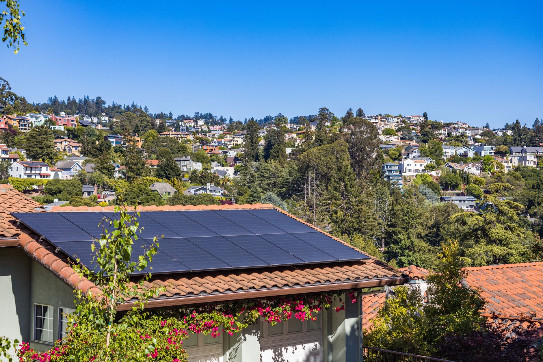 Rooftop solar panels on a suburban home under a clear sky, generating electricity