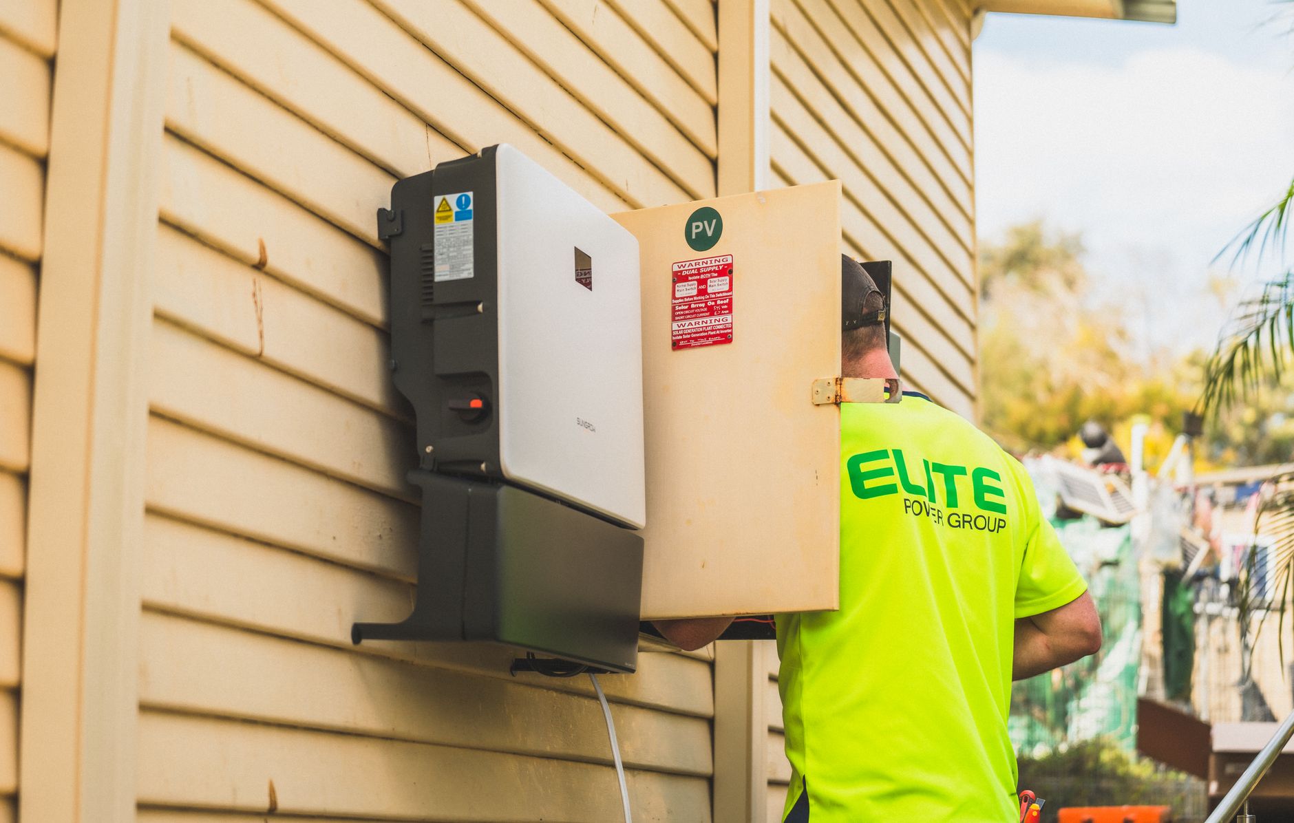 A home utility room with an electrical panel, hybrid inverter, and battery storage unit